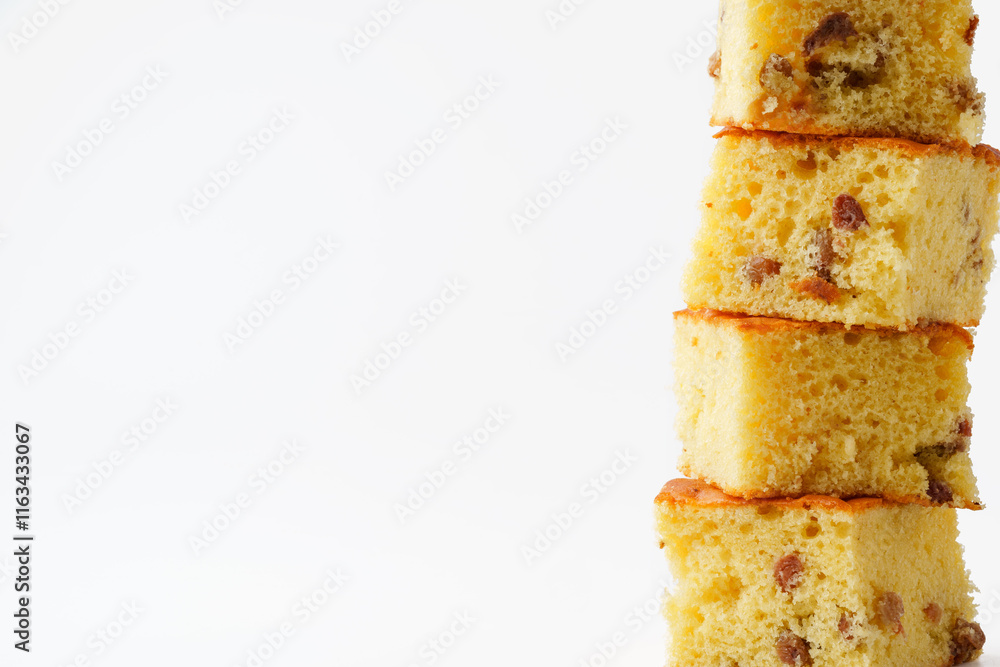 Poster stacked pieces of cake displaying a light sponge texture with bits of nuts against a plain backgroun