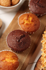 Freshly baked muffins displayed on a wooden board with assorted snacks for a cozy afternoon treat