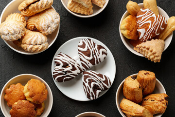 Assorted pastries and sweets arranged in bowls on a dark surface