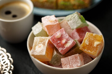 Colorful Turkish delight served with a cup of coffee on a dark table during afternoon tea