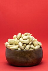 Cashew Nut in a Wooden Bowl Isolated on Red Background with Copy Space