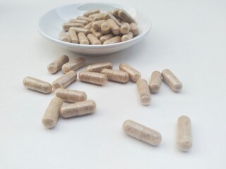 Capsule pills in a small white plate. High angle view. 