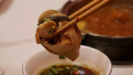 Chopsticks Holding an Oyster in a Traditional Chinese Hot Pot Scene