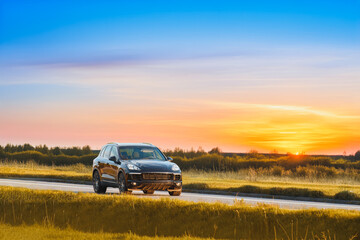 Black German SUV driving on a country road at sunset