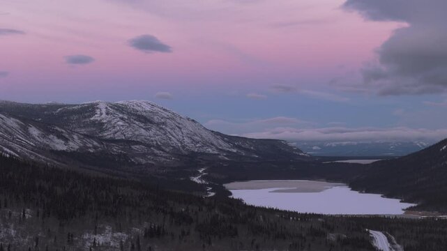 Pink Skies Over The Snowy Mountain And Bennet Lake During Winter In Yukon, Canada. - aerial shot