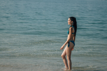 Young woman in bikini walking on seaside