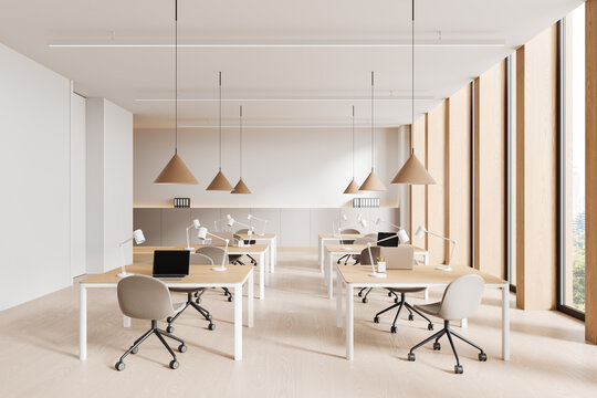 Modern coworking office interior with wooden desks, chairs, and natural light from large windows in a minimalist open space concept. 3D Rendering