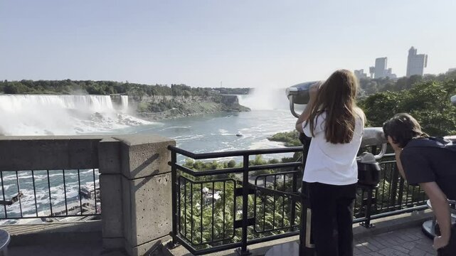 Family of Tourists using binoculars are enjoying the breathtaking view of Niagara Falls from an observation deck, experiencing the majestic power and beauty of nature in Ontario, Canada