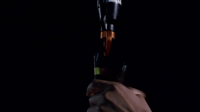 Technician prepares and inspects equipment hook on a dark stage with focused lighting