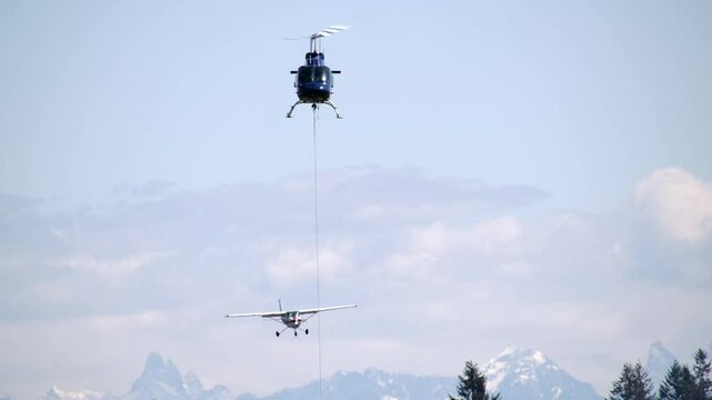 Front View of Flying Helicopter with Cable Attached and Single Engine Airplane in Approach SLOMO