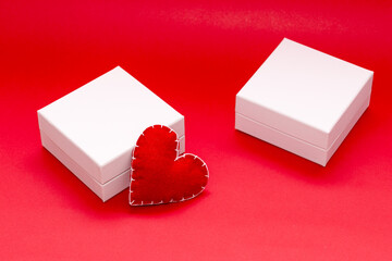 gift mockup, white gift box on bright red background and hearts next to the gift. love and relationships, valentine's day, gifts for lovers, side view