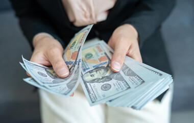 Cropped shot view of someone counting a pile of American dollar banknotes. The US Dollar is the currency of United States.