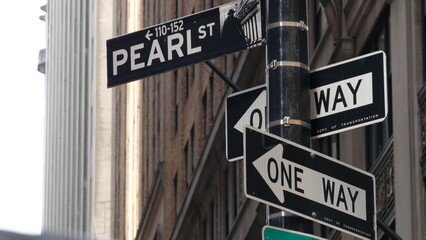 New York City, United States. Lower Manhattan Downtown Financial District. Pearl street corner road sign near Wall street Stock Exchange building, USA Stock Market. One way traffic sign, oneway arrow.