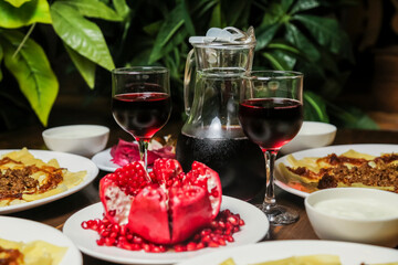 Dining table with red wine and pomegranate in a lush setting