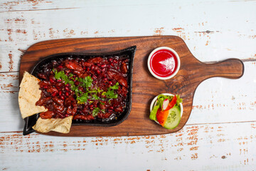 Spicy chicken dish served with garnishes on a wooden platter