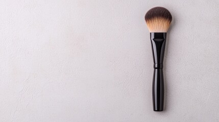 Close up of an elegant black handled makeup brush with a sleek modern design against a gray background  The cosmetic applicator tool is perfect for professional beauty and skincare routines