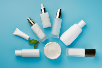 Cosmetic beauty products bottles and tubes on light blue background. Top view, flat lay. Skin care cosmetics. Copy space