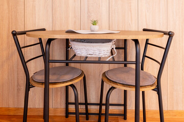 Modern chairs at small dining table, wooden wall