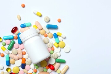 Various pills with medicine bottle on white background