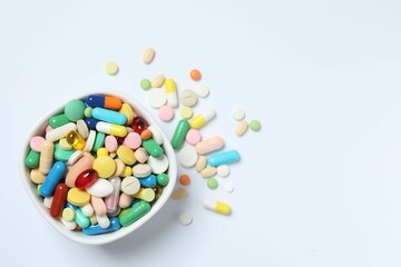 Various pills in a bowl on white background