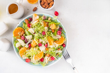 Salad bowl with lettuce, tangerines, nuts and cranberry