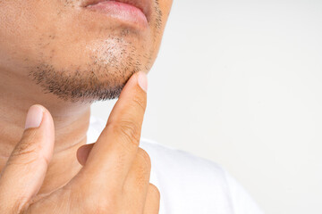 Close-up of an Asian man's chin with short facial hair, touching it thoughtfully.