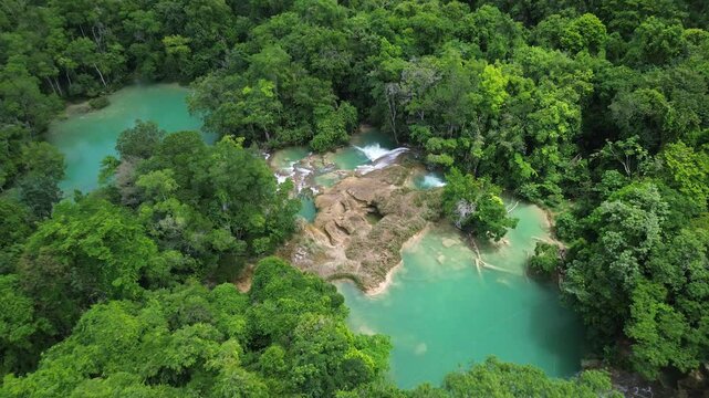 Aerial drone tilt down of turquoise waterfalls at Cascadas Roberto Barrios, surrounded by forest with open clear pools