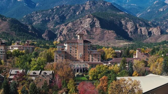 Aerial panoramic of Colorado Springs and The Broadmoor resort in peak fall colors, telephoto compression against mountains