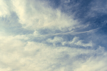 Milk-yellow clouds flutter in the wind, covering the blue sky with their veil. Natural phenomena created in the atmosphere by sunlight in the daytime, landscape backgrounds
