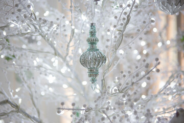 Background of a turquoise glass ornament with intricate details shines on a backdrop of luminous white branches, evoking elegance and seasonal charm