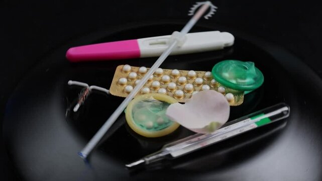 Rotating 4k video-Contraception concept -several type of birth control method on a white background with roses petals