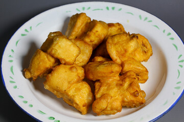 Crispy golden fritters banana served on a white plate with green accents during a festive gathering