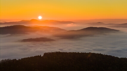 Aerial drone view of sunrise above clouds in mountains