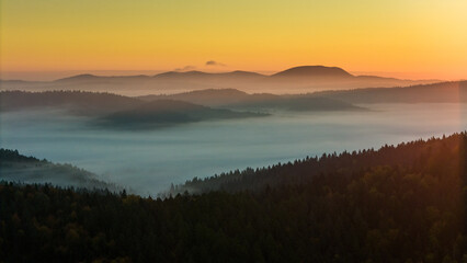 Aerial drone view of sunrise above clouds in mountains