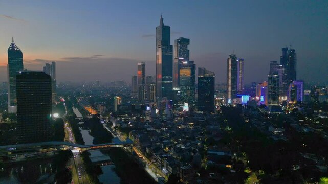 Footage of the urban skyline of Jakarta city illuminated against dusk sky at sunset, Indonesia