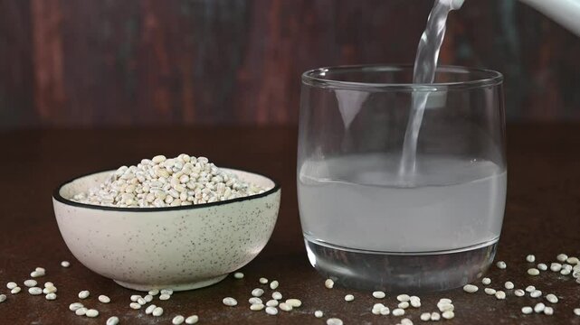 Pouring barley water in a glass cup.