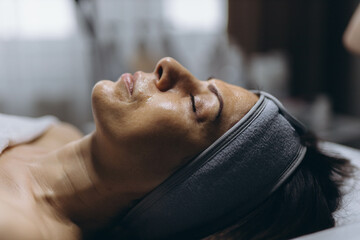 Middle aged woman getting anti aging facial peeling treatment at a cosmetic clinic