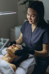 Middle aged woman receiving facial cleansing and care at a cosmetologist office
