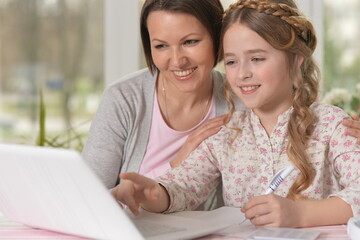 Daughter and mom use a laptop at home