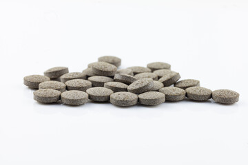 A pile of gray tablets on a white background.  Close-up view of round medication pills.