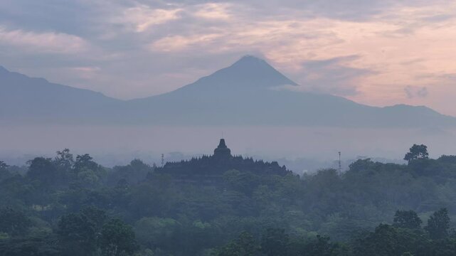 Silhouette of Borobudur temple and mountain on foggy morning, aerial view