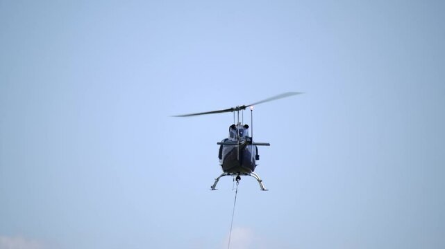 Rear View of Helicopter in Flight with Cable Attached to Belly SLOMO