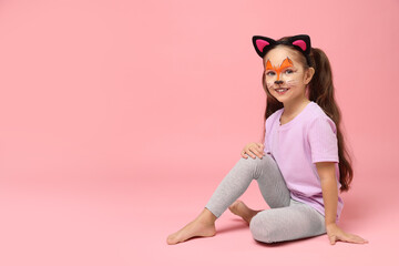 Cute girl with painted face and ears as cat on pink background, space for text