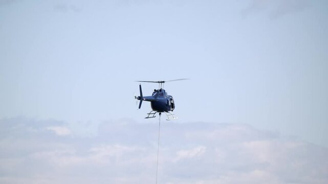 Rear View of a Hovering Helicopter Hoisting a Load - Close Up