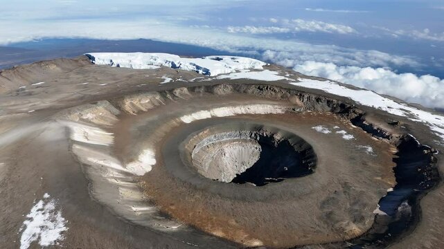 Drone shot of Uhuru Peak on Mount Kilimanjaro with the volcanic crater below. Revealing aerial shot