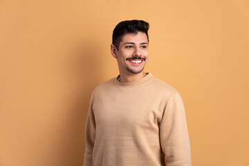joyful caucasian man thinking and looking to the side in beige background. portrait, real people concept.