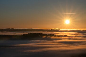 A rural sunrise winter landscape of Ramshaw Rocks shrouded in mist and fog during a cloud inversion in the Staffordshire Peak District National Park, England, UK.