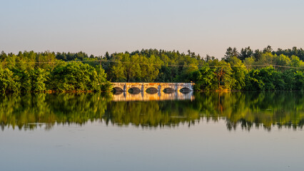 The stone inundation bridge, dating back to the 18th century, gracefully spans Vitek Pond,...