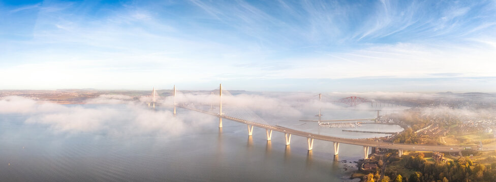 Aerial view of the bridges crossing the Firth of Forth estuary in Scotland as morning fog clears.
