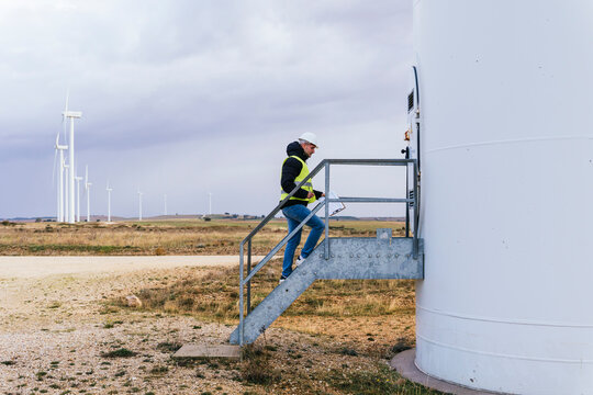 Maintenance engineer moving up on steps of wind turbine